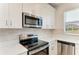 Modern kitchen featuring stainless steel appliances, white cabinets, quartz countertops, and tile backsplash at 305 Via Tuscany Ave, Sarasota, FL 34243