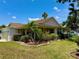 Low angle of the home showing a manicured lawn with beautiful landscaping with pink flamingos and a covered front porch at 3828 6Th W Ave, Palmetto, FL 34221