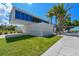 Modern architecture of Siesta Beach building with palm trees and beach access with green lawn and walkway at 385 Avenida Madera, Sarasota, FL 34242
