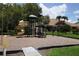 Community playground with a slide, climbing area, and a swing set surrounded by trees and grass at 4204 Overture Cir # 4204, Bradenton, FL 34209