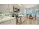 Well-lit kitchen with white cabinets, quartz countertops, stainless steel appliances, and view of the breakfast nook at 4220 Miriana Way, Sarasota, FL 34233