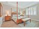 Beautiful primary bedroom features a four poster bed, decorative lamps, and a window with plantation shutters at 42250 Ramble Rd, Punta Gorda, FL 33982