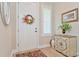 Welcoming foyer featuring a white door with a floral wreath, plantation shutters and stylish decor at 42250 Ramble Rd, Punta Gorda, FL 33982