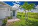 Charming front entrance with a wreath on the door, brick pathway, and manicured lawn with palm trees at 42250 Ramble Rd, Punta Gorda, FL 33982