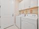 Well-organized laundry room with white washer and dryer, white cabinets, and decorative storage shelves at 42250 Ramble Rd, Punta Gorda, FL 33982