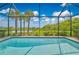 Screened-in pool area with clear blue water, surrounded by lush landscaping and a scenic view of the lake at 42250 Ramble Rd, Punta Gorda, FL 33982