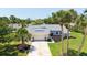 View of a single-story home with well-maintained landscaping and a two-car garage amidst palm trees and blue sky at 4308 Kingston Loop, Sarasota, FL 34238