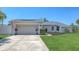Charming single-story home showcasing a well-manicured lawn and a spacious two-car garage under a blue sky at 4308 Kingston Loop, Sarasota, FL 34238