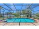 Sparkling screened-in pool surrounded by lush landscaping and a brick patio at 4308 Kingston Loop, Sarasota, FL 34238