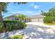 Inviting single-story home with a three-car garage, palm trees, shutters, and a concrete driveway at 5373 Anthony Ln, Sarasota, FL 34233