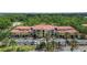 A multi-story building with a red tile roof, lush landscaping, and ample parking at 5401 Bentgrass Dr # 1-113, Sarasota, FL 34235