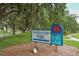 Welcoming Colonial Oaks Park sign with blue accents and a picturesque, lush green surrounding landscape at 5613 Sweetwater Oak Dr, Sarasota, FL 34232