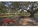 Scenic picnic area featuring red picnic tables and views of a peaceful pond and moss-draped trees at 5613 Sweetwater Oak Dr, Sarasota, FL 34232