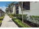 Condo exterior with a paver walkway, lush landscaping, and palm trees at 5624 Palmer Cir # 206, Bradenton, FL 34211