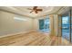 Light, airy main bedroom with wood floors, tray ceiling, fan, and sliding doors leading to the pool area at 6914 Dominion Ln, Lakewood Ranch, FL 34202