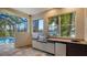 This outdoor kitchen features a stainless steel grill, mini fridge, sink, and views of the pool and lush foliage at 6914 Dominion Ln, Lakewood Ranch, FL 34202