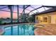 Stunning screened pool and spa with an outdoor kitchen and serene lake views at dusk at 6914 Dominion Ln, Lakewood Ranch, FL 34202