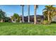 Screened-in lanai spans the rear of this home, surrounded by tropical palms and a verdant lawn at 6914 Dominion Ln, Lakewood Ranch, FL 34202