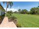 Lush backyard view with manicured lawn, mature trees, and colorful landscaping at 7331 Villa D Este Dr, Sarasota, FL 34238