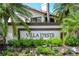 Welcome to Villa d'Este! An inviting entrance with mature palms and colorful flowers at 7331 Villa D Este Dr, Sarasota, FL 34238
