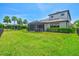 Spacious backyard with black metal fence, palm trees, well-maintained lawn, and a screened patio at 8272 Summer Night Rd, Sarasota, FL 34241