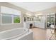 Bright bathroom featuring double sinks, large soaking tub and view to the main bedroom at 8272 Summer Night Rd, Sarasota, FL 34241