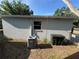 View of the side of the house showcasing the AC unit and trash bins with a yard at 8291 57Th N St, Pinellas Park, FL 33781