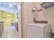 Laundry room with front-load washer and overhead shelving, next to a door to the kitchen at 8341 38Th Street Cir E # 303, Sarasota, FL 34243