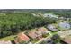 Aerial view of houses with tile roofs, lush greenery, and a tranquil lake in a serene neighborhood at 9008 Brookfield Ter, Bradenton, FL 34212