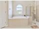 Bright bathroom features a soaking tub under an arched window and a glass-enclosed shower at 9008 Brookfield Ter, Bradenton, FL 34212