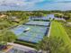 Aerial view of tennis courts and a scenic pond creating a tranquil recreational setting at 9008 Brookfield Ter, Bradenton, FL 34212