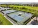 Aerial view of pristine tennis courts surrounded by lush landscaping and a picturesque pond at 9008 Brookfield Ter, Bradenton, FL 34212