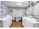 Laundry room featuring multiple washers, dryers, folding table, and wood-look floors at 9393 Midnight Pass Rd # 603, Sarasota, FL 34242