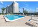 Community pool with lounge chairs, lush greenery, and a view of the building under blue sky at 9393 Midnight Pass Rd # 603, Sarasota, FL 34242