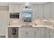 Well-lit kitchen showcasing white cabinetry, stainless steel appliances, and a view of the lovely garden at 9822 Desoto Ct, Bradenton, FL 34210