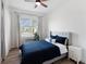 Cozy bedroom with wood floors, large window, ceiling fan, a padded headboard bed dressed in blue, and white curtains at 10030 Degas Ter, Bradenton, FL 34212