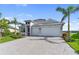 Beautiful home featuring a paved driveway, two-car garage, and tropical landscaping under a clear blue sky at 10030 Degas Ter, Bradenton, FL 34212