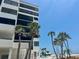 Exterior shot of condo building overlooking ocean and beach front property with palms and a pool at 1100 Benjamin Franklin Dr # 802, Sarasota, FL 34236