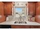 Kitchen featuring stainless steel sink, brown cabinets, and a view to the backyard at 1190 Jamaica Rd, Venice, FL 34293