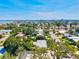 An aerial view of a neighborhood with lush trees and a glimpse of the ocean in the distance at 1324 Augusta S Ln, St Petersburg, FL 33707