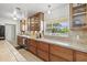 A sunlit kitchen featuring wood cabinetry, tiled countertops, and a large window providing natural light at 1324 Augusta S Ln, St Petersburg, FL 33707