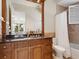 Elegant bathroom with a tub and shower combination featuring tile surround, a wood vanity, and granite countertop at 1423 & 1435 Hillview Dr, Sarasota, FL 34239