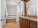 Bright bathroom featuring a soaking tub with shower, natural stone floor, and wood vanity with a granite countertop at 1423 & 1435 Hillview Dr, Sarasota, FL 34239