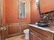 Artsy bathroom with terracotta walls, a high window, a dark bowl sink, and wood cabinetry with marble countertops at 1423 & 1435 Hillview Dr, Sarasota, FL 34239