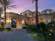 Luxurious home entrance with stone accents, a porte-cochere, and manicured gardens, illuminated by landscape lighting at 1423 & 1435 Hillview Dr, Sarasota, FL 34239