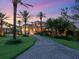 Elegant home showcasing a curved driveway, lush landscaping, and a grand entrance under a colorful evening sky at 1423 & 1435 Hillview Dr, Sarasota, FL 34239