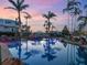 Luxury pool with rock waterfall feature, palm trees and beautiful landscaping at dusk at 1423 & 1435 Hillview Dr, Sarasota, FL 34239