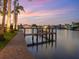Picturesque waterfront view with a private dock, palm trees, and neighboring homes under a vibrant sunset at 1423 & 1435 Hillview Dr, Sarasota, FL 34239