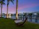Relaxing waterfront view with hammock and private dock, framed by palm trees under a dusk sky at 1423 & 1435 Hillview Dr, Sarasota, FL 34239