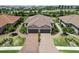 Aerial view of the home with a double garage, lush landscaping, and a brick-paved driveway at 15752 Sacile Ln, Bradenton, FL 34211